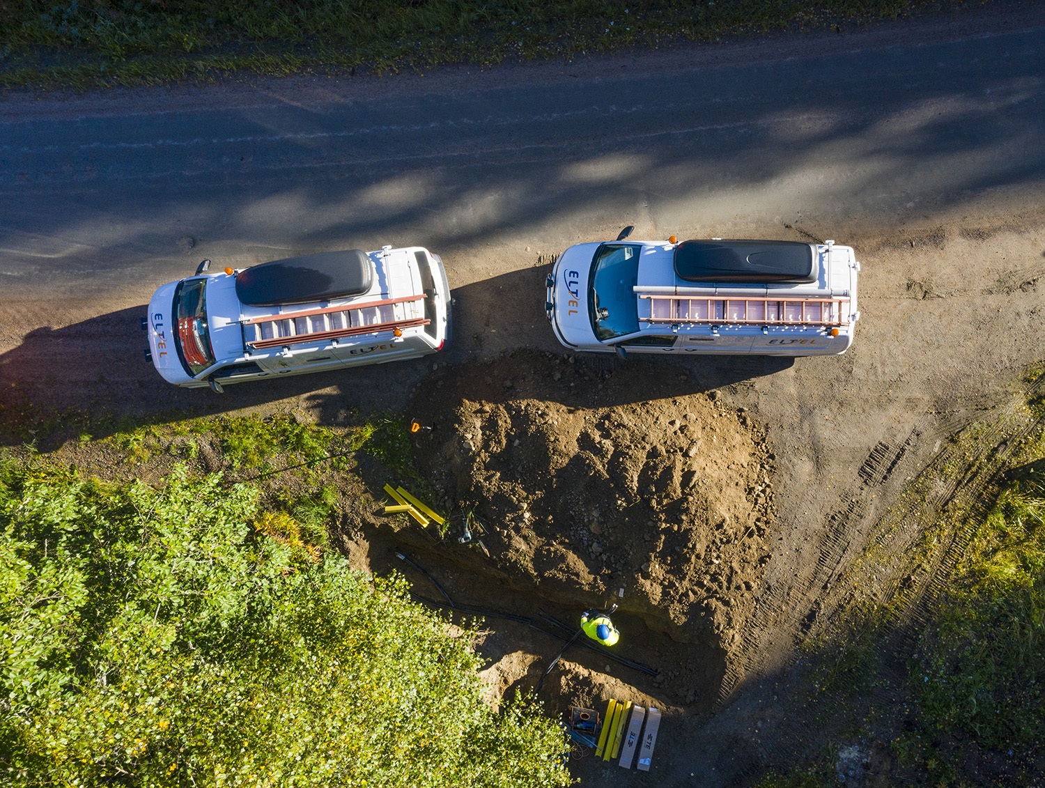 Kaksi Eltelin autoa on tien reunassa.